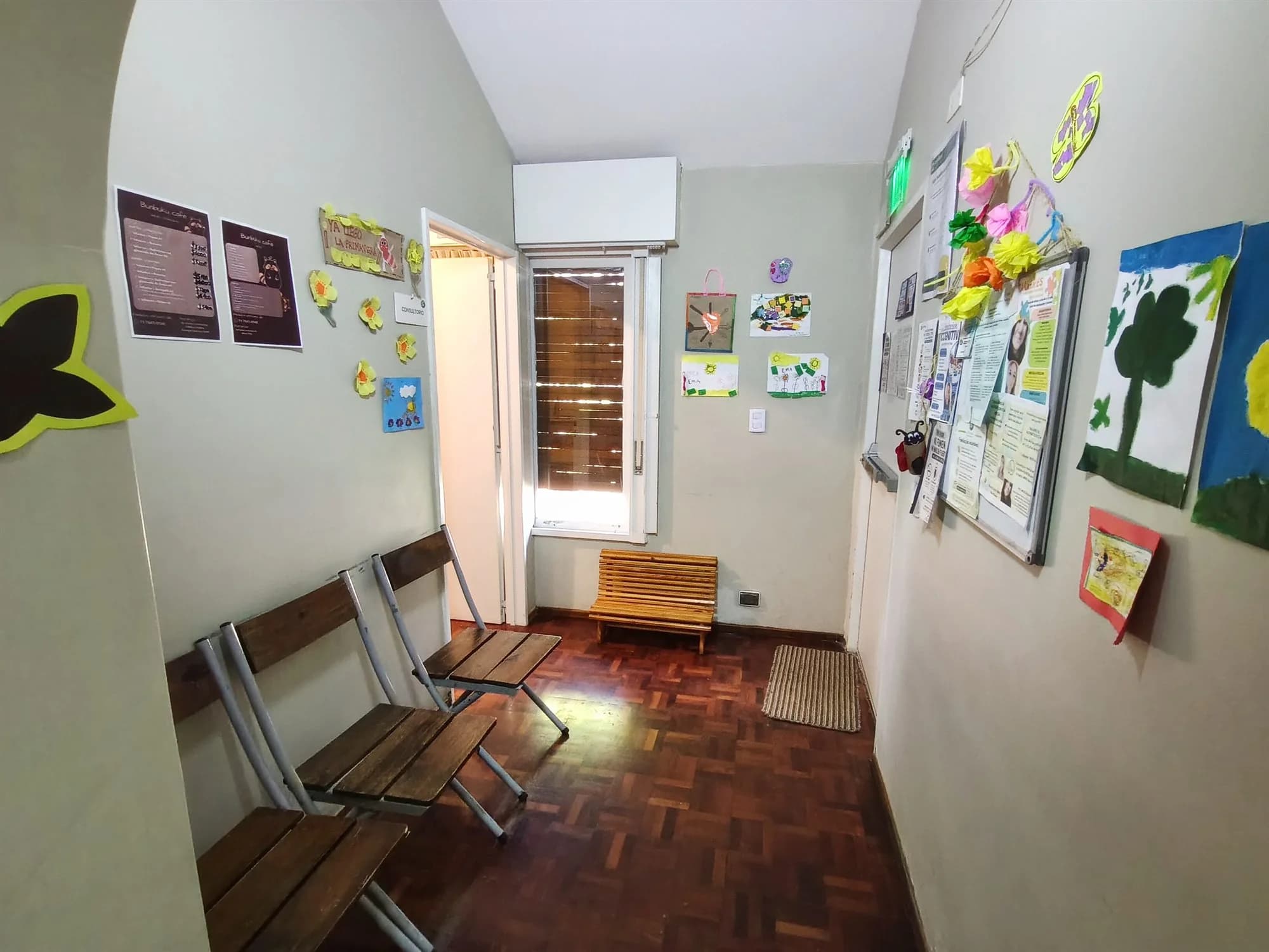 Sala de espera con sillas infantiles y trabajos expuestos